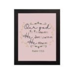 Psalm 115:3 Bible verse wall art with elegant black cursive text, vine decorations, and a soft pink background for a warm, spiritual design. hung on the wall in a black frame