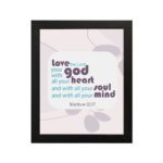 Love the Lord your God with all your heart, soul, and mind Matthew 22:37 Bible Wall Art with purple and teal text, abstract shapes, and leaf motifs on light cream background displayed on the wall in a black frame in a white background