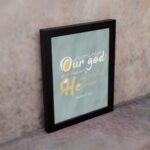 Christian wall art with Psalm 115:3 verse in gold and white text, set against a light sage green background, with elegant script fonts. displayed on the wall in a black frame