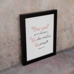 Psalm 115:3 Bible verse wall art with pink cursive and black text, floral accents, and a white background for a modern, spiritual design. displayed on the wall in a black frame