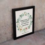 Rejoice always, pray without ceasing, give thanks in all circumstances 1 Thessalonians 5:16-17 Bible Wall Art with delicate floral wreath in pastel colors, light cream background displayed on the wall in a black frame