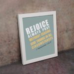 Rejoice always, pray without ceasing, give thanks in all circumstances 1 Thessalonians 5:16-17 Bible Wall Art with white and yellow text on muted teal background, bold design displayed on the wall in a white frame