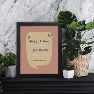 Be Joyful Always Pray Continually Give Thanks Bible Wall Art with sandal background and green leaf accents. Perfect Christian home decor. displayed on the table in a black frame