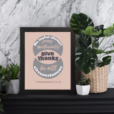 Be Joyful Always Pray Continually Give Thanks in All Circumstances Bible wall art with bold text and a beige background featuring a gray circle. displayed on the table in a black frame