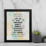 Fruit of the Spirit Bible verse wall art with black text and pastel watercolor background, Galatians 5:22-23. displayed on the wall in a black frame