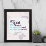 Love the Lord your God with all your heart, soul, and mind Matthew 22:37 Bible Wall Art with purple and teal text, abstract shapes, and leaf motifs on light cream background displayed on the wall in a black frame