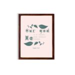 Christian wall art with Psalm 115:3 Bible verse on a light pink background with dark green leaf design and green font and brown framed displayed on the wall