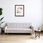 Christian wall art with Psalm 115:3 Bible verse on a light pink background with dark green leaf design and green font and brown framed hung on the wall above the sofa