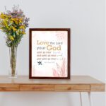 Love the Lord your God with all your heart, soul, and mind Matthew 22:37 Bible Wall Art with golden and black text, pastel pink abstract patterns, and leaf accents, displayed on the table