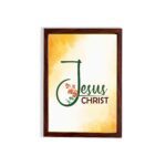 Jesus Christ text in green script with red floral accents on a glowing yellow-orange background, framed in black. hung on the wall in a brown frame