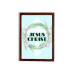 Infidu Jesus Christ Bible Wall Art with JESUS CHRIST text in a mint blue background surrounded by a floral wreath. hung on the wall in a brown frame