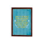 Christian wall art with Proverbs 31:25 verse in bold yellow text on a dark blue background with floral accents hung on the wall in a brown frame