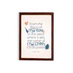 Bible verse wall art displaying From the Rising of the Sun to the Place Where It Sets, The Name of the Lord Is to Be Praised. hung on the wall in a brown frame