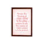 Bible wall art featuring Psalm 113:3 with bold text and a soft pink background, highlighting The Sun and The Lord. hung on the wall in a brown frame