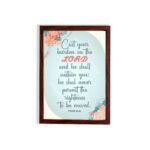 Cast Your Burden on the Lord Psalm 55:22 Christian wall art with teal and coral text on a mint green background with floral accents. hung on the wall in a brown frame