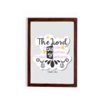 Bible wall art with The Lord Is My Rock, My Fortress, and My Deliverer in colorful pastel text on a light grey background with decorative elements. hung on the wall in a brown frame