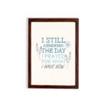 Christian wall art featuring the phrase I Still Remember The Days I Prayed For What I Have Now with floral designs in light blue. hung on the wall in a brown frame