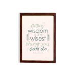 Infidu wall art with Proverbs 4:7 text surrounded by green leaves on a beige background. Elegant and minimal design. hung on the wall in a brown frame