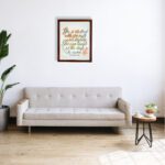 Christian wall art featuring the quote She is clothed with strength and dignity; she can laugh at the days to come from Proverbs 31:25, with an elegant design and pastel colors. displayed on the wall in a brown frame