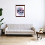 His Grace Is Enough Christian wall art with bold dark purple text and a soft gradient background in pink, purple, and blue. displayed on the wall in a brown frame