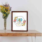 God Is Within Her She Will Not Fall Psalm 46:5 Bible Verse Wall Art with colorful flowers and modern design displayed on the table in a brown frame