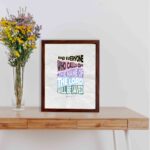 Acts 2:21 Bible verse wall art with pastel-colored bold text on a light gray background. And everyone who calls on the name of the Lord. displayed on the table in a brown frame