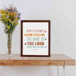 Bible wall art with Acts 2:21 verse, featuring pastel polka dots and bold text, designed to inspire and uplift your home decor. displayed on the table in a brown frame