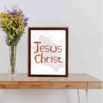 Jesus Christ Bible wall art with hand-drawn brown lettering and a minimalist white-gray watercolor background in a black frame. displayed on the wall in a brown frame