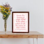 Bible wall art featuring Psalm 113:3 with bold text and a soft pink background, highlighting The Sun and The Lord. displayed on the table in a brown frame