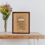 Christian wall art featuring Psalm 55:22, with a warm brown background, dark text, and elegant scrollwork. Perfect for home decor. displayed on the table in a brown frame