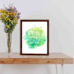 Infidu wall art featuring the quote God Is Within Her, She Will Not Fall with a light green diamond background and white text. displayed on the table in a brown frame