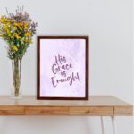 His Grace Is Enough Bible Wall Art with purple text on a lilac background. displayed on the table in a brown frame