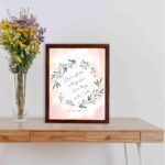 Infidu Set Your Affection On Things Above Bible Wall Art with floral wreath and pink background. displayed on the table in a brown frame