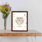 Colossians 3:2 Bible verse wall art with floral design and bold lettering, featuring the words Set Your Affection on Things Above. displayed on the table in a brown frame