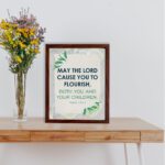 Infidu Christian wall art featuring Psalm 115:14 with bold text, green highlights, and leaf designs on a light gray background. displayed on the table in a brown frame