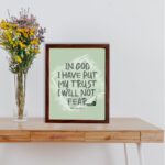 In God I Have Put My Trust, I Will Not Fear Psalm 56:4 bold Christian wall art with green background and brushstroke lettering displayed on the table in a brown frame