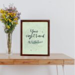 Your Right Hand Upholds Me Psalm 63:8 Christian wall art with dark gray text and light green floral elements on a pale green displayed on the table in a brown frame background.