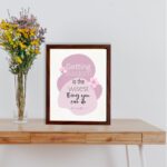 Christian wall art featuring the quote Getting Wisdom Is The Wisest Thing You Can Do from Proverbs 4:7, with pink flowers and soft colors. displayed on the table in a brown frame