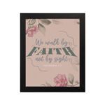 We Walk By Faith Not By Sight Christian Wall Art with pink roses and gray leaves on a soft pink background hung on the wall in a black frame.