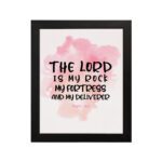 Bible wall art featuring The Lord Is My Rock, My Fortress, and My Deliverer in black handwritten-style lettering on a soft pink watercolor background. hung on the wall in a black frame