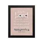 Christian wall art featuring Psalm 115:14, with large text, floral decorations, and a warm beige background. hung on the wall in a black frame