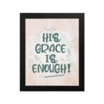 Christian wall art featuring the phrase His Grace Is Enough in teal lettering on a soft pink background with decorative swirls. hung on the wall in a black frame