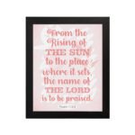 Bible wall art featuring Psalm 113:3 with bold text and a soft pink background, highlighting The Sun and The Lord. hung on the wall in a black frame