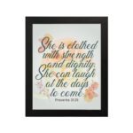 Christian wall art featuring the quote She is clothed with strength and dignity; she can laugh at the days to come from Proverbs 31:25, with an elegant design and pastel colors. hung on the wall in a black frame