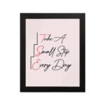 Infidu Take A Small Step Everyday wall art with a gray and light pink background black and red text and a black frame hung on the wall. Inspiring decor for any workspace.