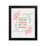 Infidu When You Can't Find The Sunshine Be The Sunshine wall art with a white background and red floral accents and black frame hung on the wall Inspiring decor for home offices.