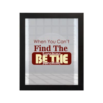 Infidu When You Can't Find The Sunshine Be The Sunshine wall art with a gray and white background and red text and black frame hung on the wall Inspiring decor for any workspace.