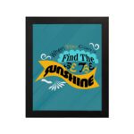 Infidu When You Can't Find the Sunshine, Be the Sunshine Office Wall Art featuring black, yellow, and blue text on a light blue background with decorative elements, framed in black hung on the wall. Perfect for inspirational quote wall art, office wall art, and home decor.