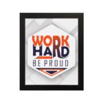 Inspirational quote wall art featuring Work Hard Be Proud with orange and navy blue text on a light gray and light green background and black frame hung on the wall. Perfect for home offices.