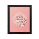 And Everyone Who Calls On The Name Of The Lord Will Be Saved Acts 2:21 Bible Verse Wall Art with pink flowers and soft pink background. hung on the wall in a black frame